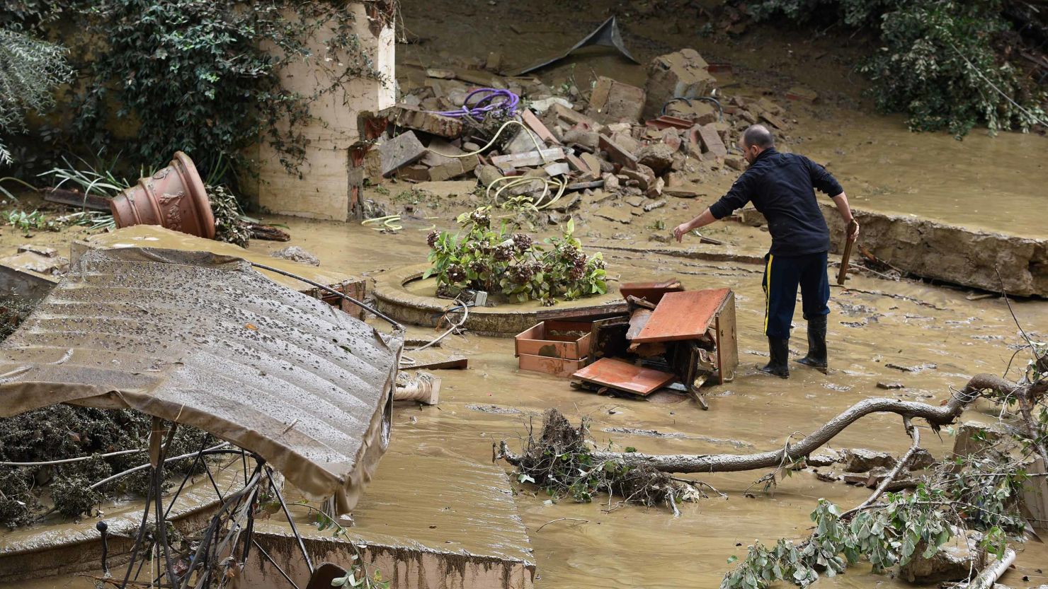 A man piles wrecked furniture outside his home in the Livorno area, flooded after heavy rain, on September 10, 2017.