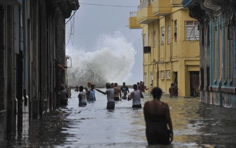 People wade through a flooded street as a wave crashes in Havana on Sunday, September 10.