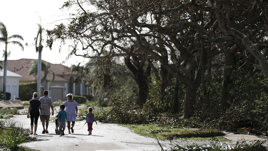 A family walks through a street littered with fallen branches in Marco Island on Monday, a day after Hurricane Irma struck.