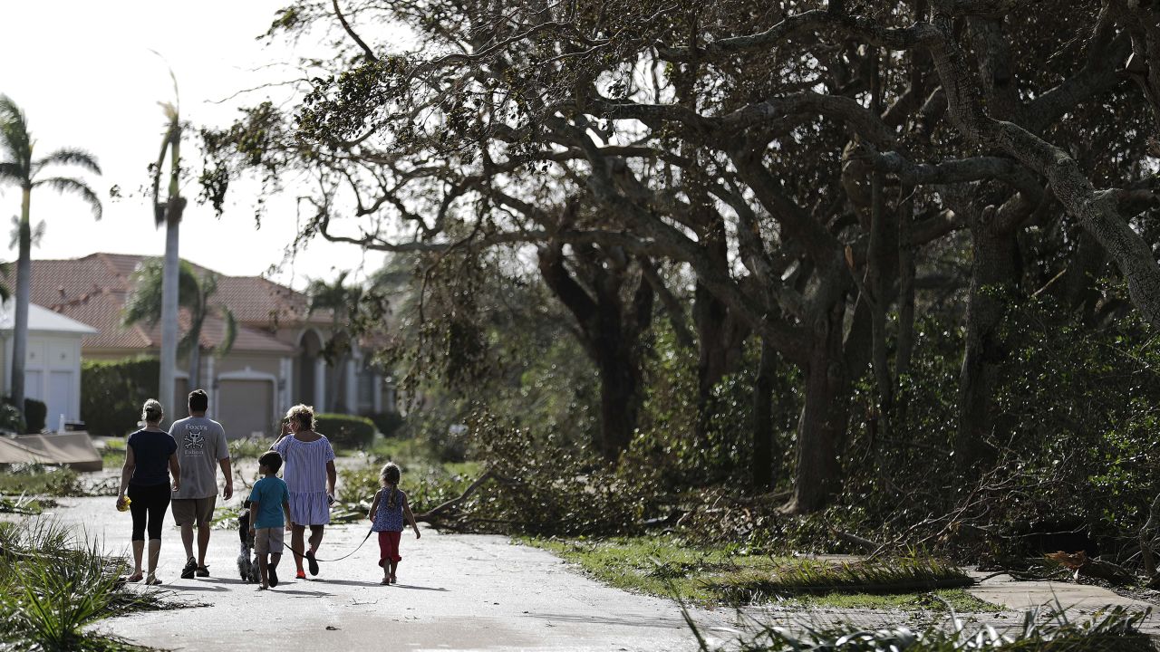 A family walks through a street littered with fallen branches in Marco Island on Monday, a day after Hurricane Irma struck.