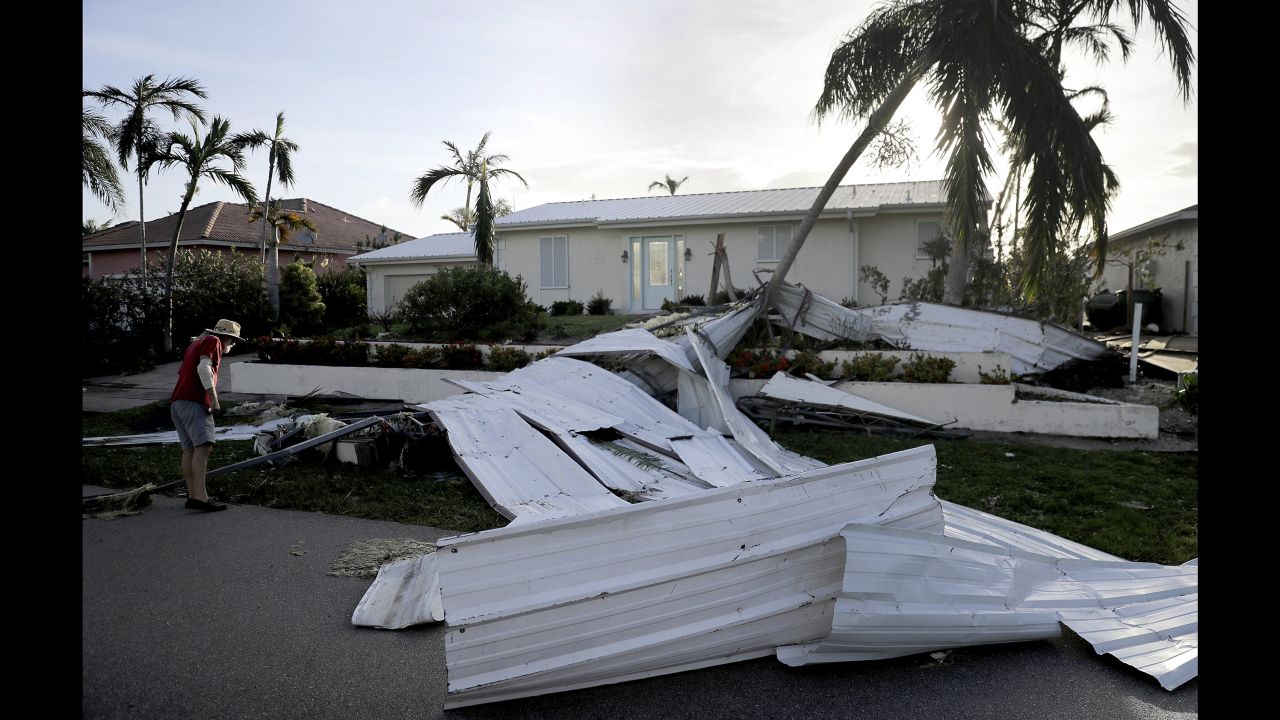 A roof is strewn across a home's lawn as Rick Freedman checks his neighbor's damage.