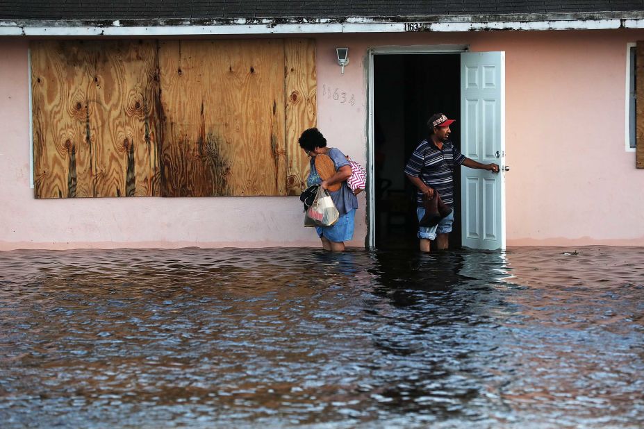 People step out of their flooded home in Fort Myers, Florida, on September 11.