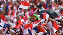 Spectators wave Singaporean national flags during their country's 52nd National Day parade and celebration in Singapore on August 9, 2017. / AFP PHOTO / ROSLAN RAHMAN        (Photo credit should read ROSLAN RAHMAN/AFP/Getty Images)