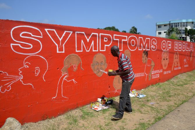Street artist Stephen Doe paints an educational mural about Ebola symptoms in Liberia in 2014. 