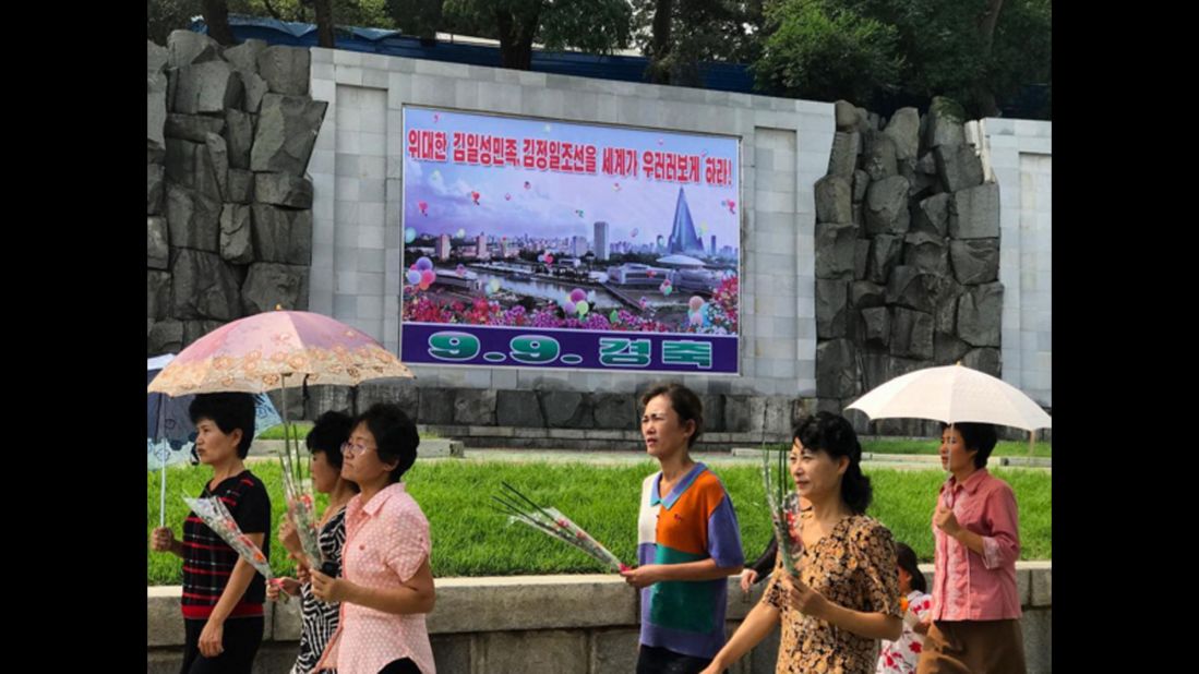 Pyongyang residents walk past a poster marking the 69th DPRK Foundation Day on September 9. It reads "Let the entire world look up to the great Kim Il Sung nation and Kim Jong Il Korea."