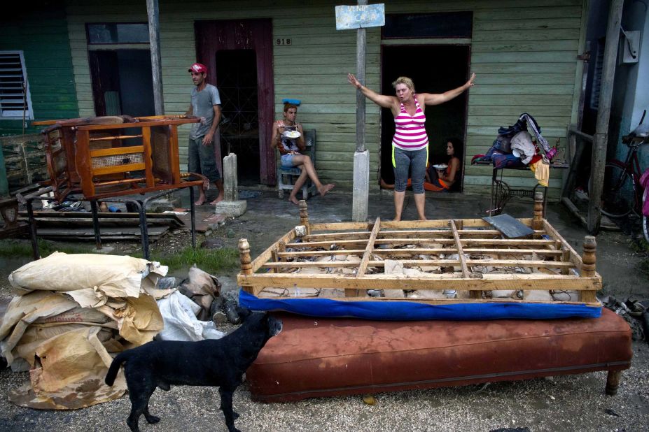 A woman stands next to her water-logged belongings that had been laid out to dry in front of her home in Isabela de Sagua on September 11.