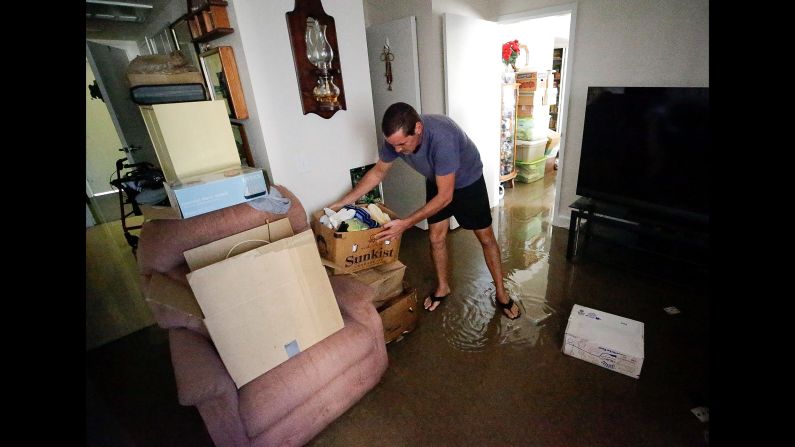 Joseph Dupuis III stacks boxes off the floor in his parents' water-logged apartment in Jacksonville, Florida, on September 12.