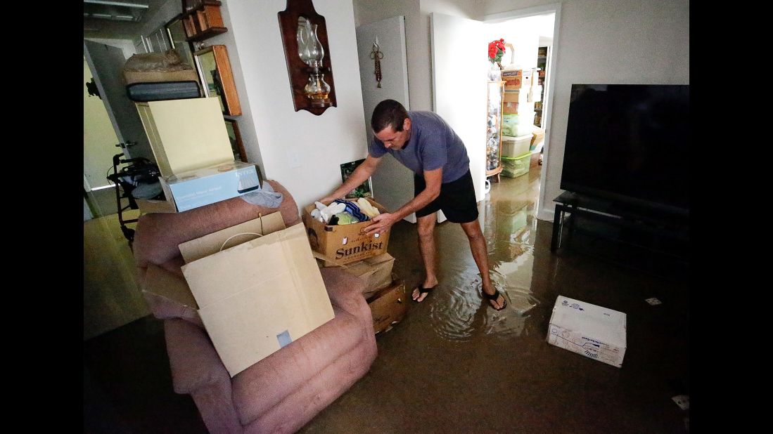 Joseph Dupuis III stacks boxes off the floor in his parents' water-logged apartment in Jacksonville, Florida, on September 12.