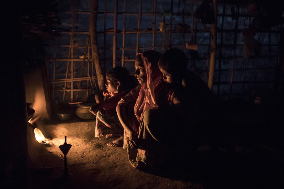 Rohingya Muslims who have been living in Bangladesh for more than a year sit by a fire at a shelter.
