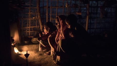 Rohingya Muslims who have been living in Bangladesh for more than a year sit by a fire at a shelter.