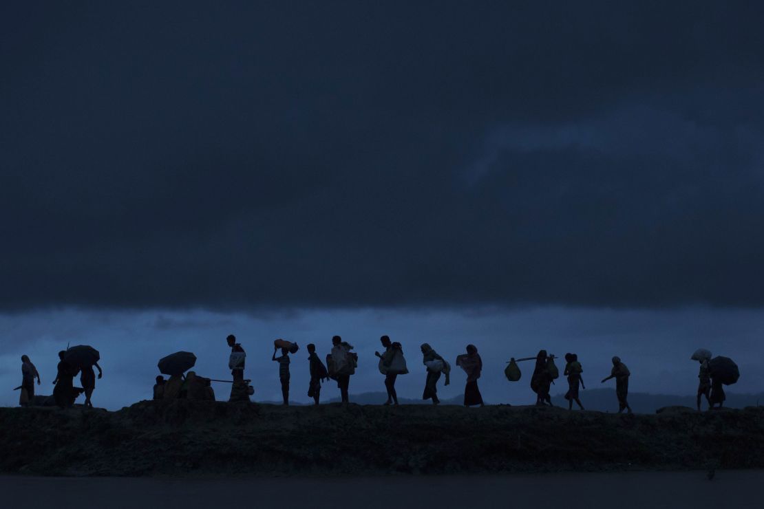 Rohingya refugees walk across paddy fields at dusk after crossing the border from Myanmar.