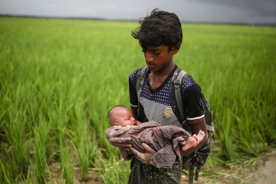 A Rohingya child holds a baby on September 12, as refugees wade through the Naf River in Bangladesh.