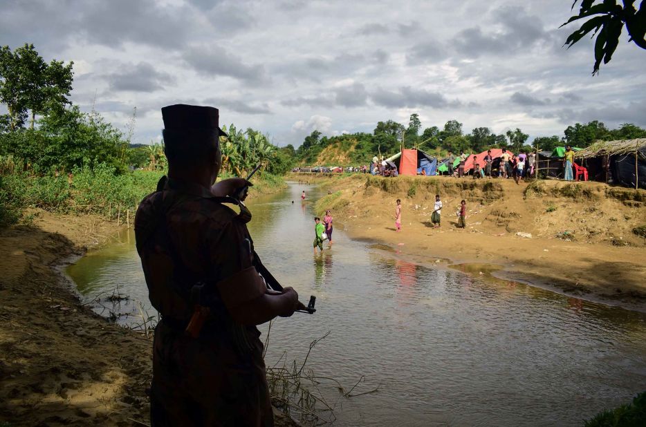 A Bangladeshi border guard orders Rohingya refugees to return to the Myanmar side of a small canal on August 29. Bangladesh has been struggling to cope with the influx of refugees.