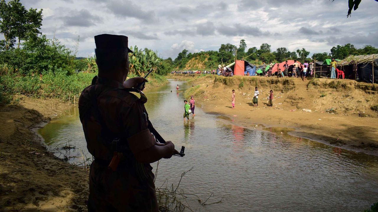 This August 29, 2017 photo taken from Nykkhongchhari near the Bangladeshi town of Ukhiya shows a Bangladeshi border guard ordering Rohingya refugees to return to the Myanmar side of a small canal between the two countries.
At least 6,000 Rohingya civilians fleeing renewed violence in Myanmar are stranded near the border with Bangladesh which is blocking their entry, a senior Bangladeshi official said August 29, as the United Nations urged Dhaka to let them in.
 / AFP PHOTO / Emrul Kamal        (Photo credit should read EMRUL KAMAL/AFP/Getty Images)