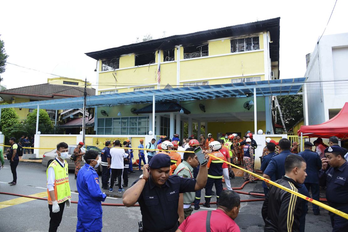 Police and rescue personnel work at an Islamic religious school in Kulala Lumpur that was cordoned off after a fire on September 14.