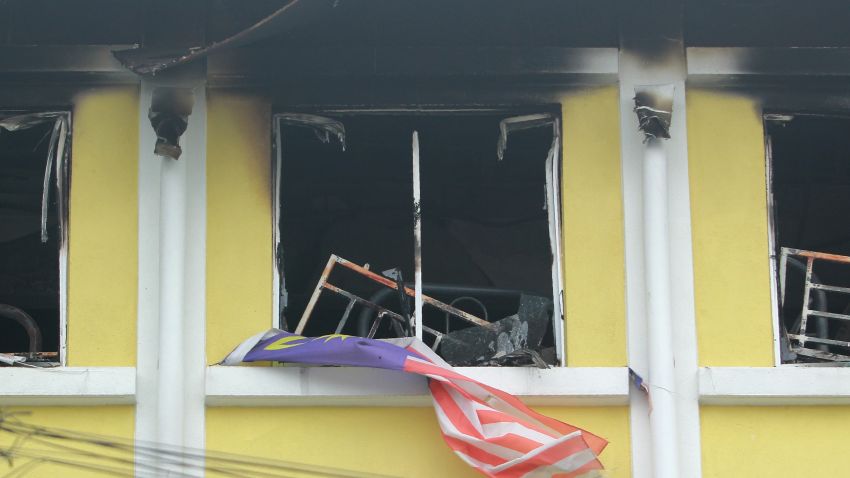 A Malaysian national flag flutters outside burnt windows of the Darul Quran Ittifaqiyah religious school in Kuala Lumpur on September 14, 2017. 
Twenty-five people, mostly teenage boys, were killed on September 14 when a blaze tore through a Malaysian religious school, in what officials said was one of the country's worst fire disasters for years. / AFP PHOTO / SADIQ ASYRAF        (Photo credit should read SADIQ ASYRAF/AFP/Getty Images)