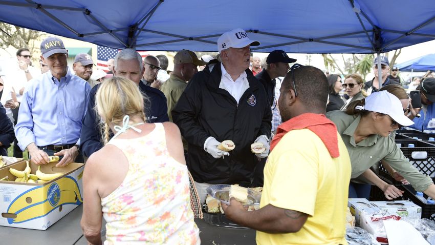 President Donald Trump, with Florida Gov. Rick Scott, left, Vice President Mike Pence, second left, and first lady Melania Trump, helps serve food to people affected by Hurricane Irma in Naples, Florida, on Thursday.