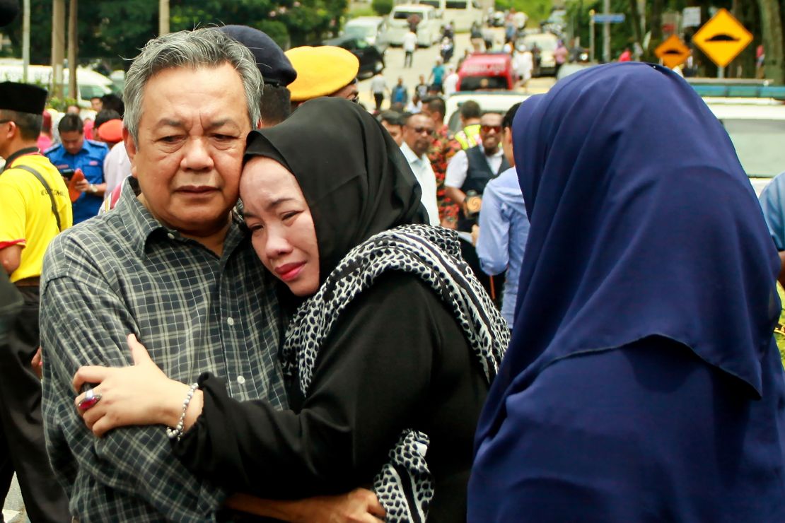 Nik Azlan Nik Abdul Kadir (left), the father of one of the victims, comforts his wife outside the school in Kuala Lumpur on September 14.