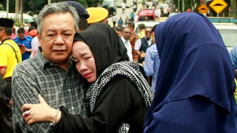 Nik Azlan Nik Abdul Kadir (left), the father of one of the victims, comforts his wife outside the school in Kuala Lumpur on September 14.