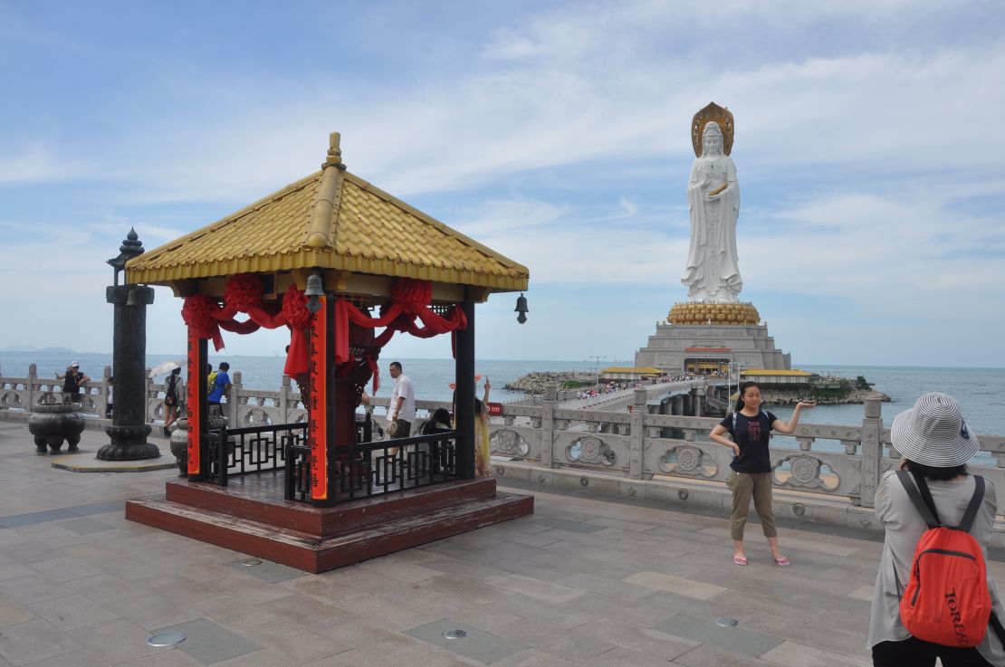 A woman poses for a photo in front of a 108-meter statue of Guanyin, the Buddha of the Southern Seas.