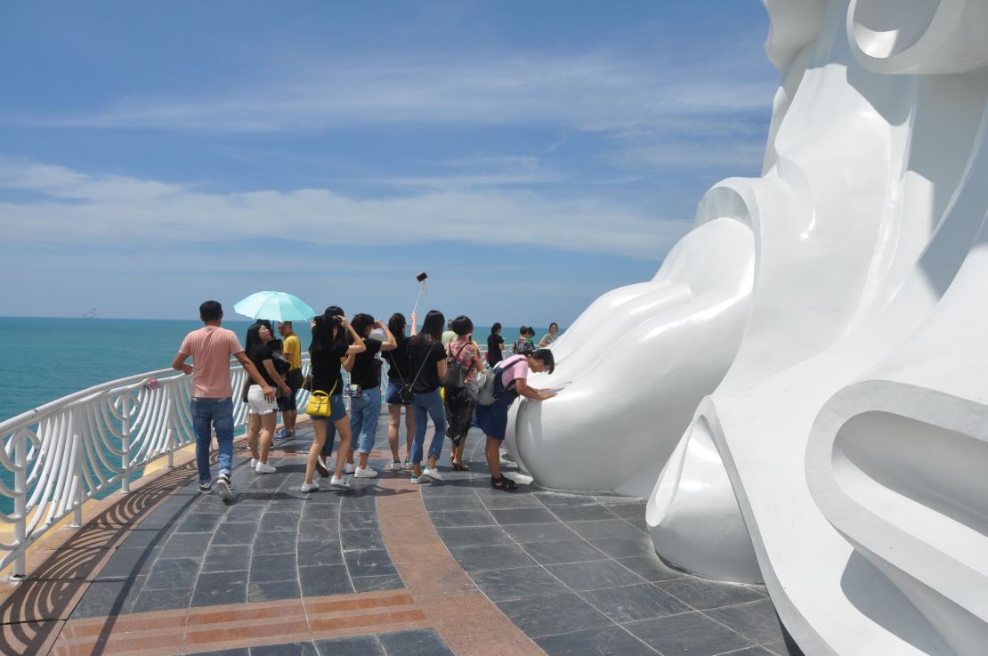 A woman prays to the Bodhisattva Guanyin at her huge statue in southern Sanya, Hainan.