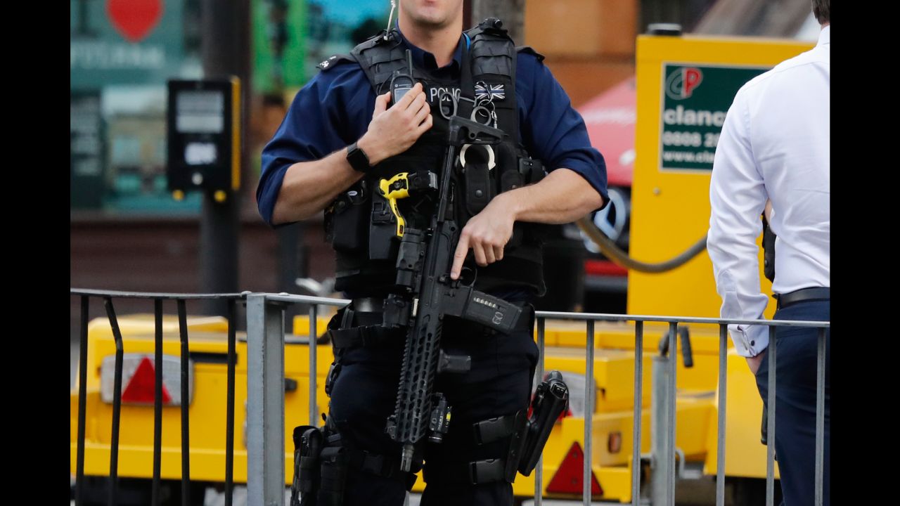 An armed police officer stands nearby after an incident on a tube train at Parsons Green station.