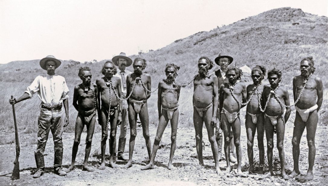 An archival image shows the type of scene that inspired Semu's work. Taken in 1896, this photo shows Aboriginal prisoners outside a jail in Roebourne, Western Australia.