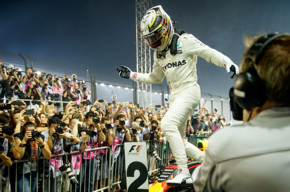 Walking on air: Hamilton leaps off his car following another hugely impressive drive at the Marina Bay Street Circuit. The Briton now leads the drivers' championship by 28 points from Sebastian Vettel.