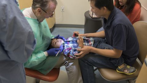 Ray Stewart, a pediatric dental professor at the University of California-San Francisco, examines Matthew Mai, 2, with the help of his parents, Sean and Tina Mai.