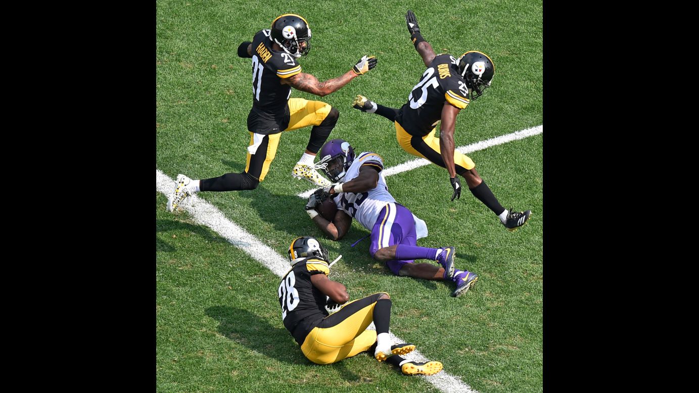 Pittsburgh defensive backs Joe Haden and Artie Burns leap over Minnesota running back Dalvin Cook after Cook was tackled just short of the goal line on Sunday, September 17.