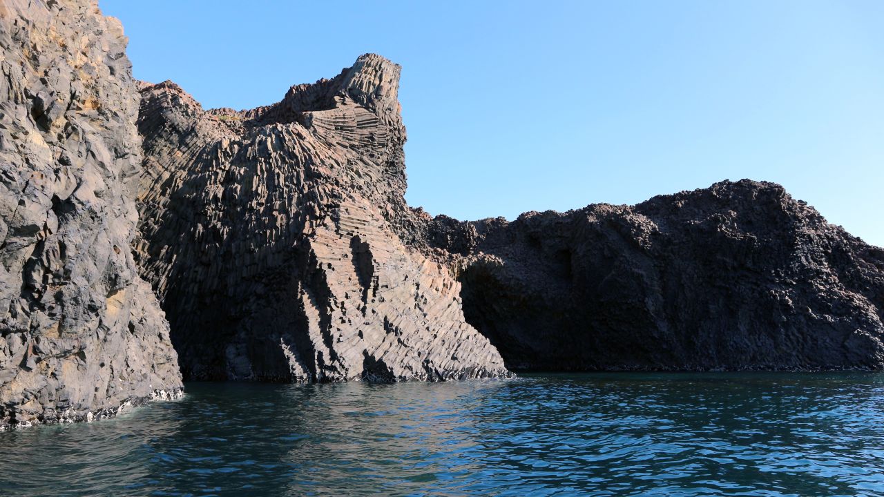 The basalt columns of the island look like twisted stairs emerging from the deep blue waters.