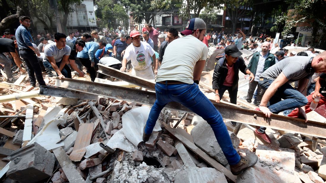 People remove debris off a building that collapsed in Mexico City.