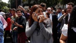 A woman speaks on her cell phone as people evacuated from an office building gather on Reforma Avenue after an earthquake in Mexico City, on September 19.