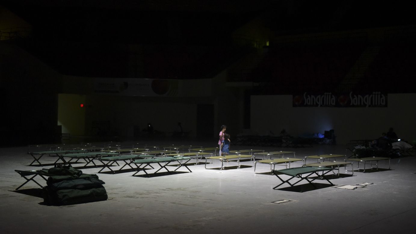 Two girls play on cots at the Humacao Arena.