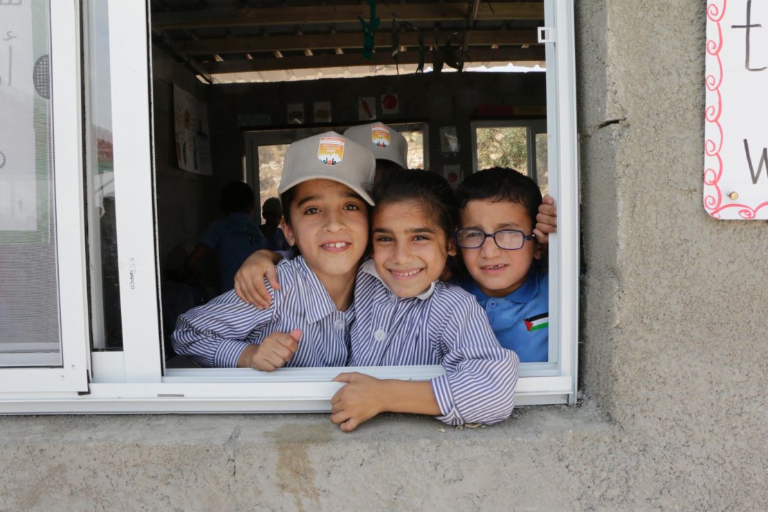 Nine-year-old Sundus Zawahra, left, and eight-year-old Nagham Ali, right, peer through the window of their fourth grade class with a friend at the school.