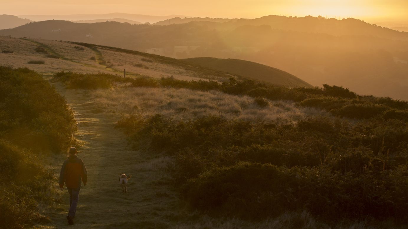 <strong>Pentyrch, UK: </strong>A man and his dog walk at dawn through the Welsh countryside on the first day of September. 