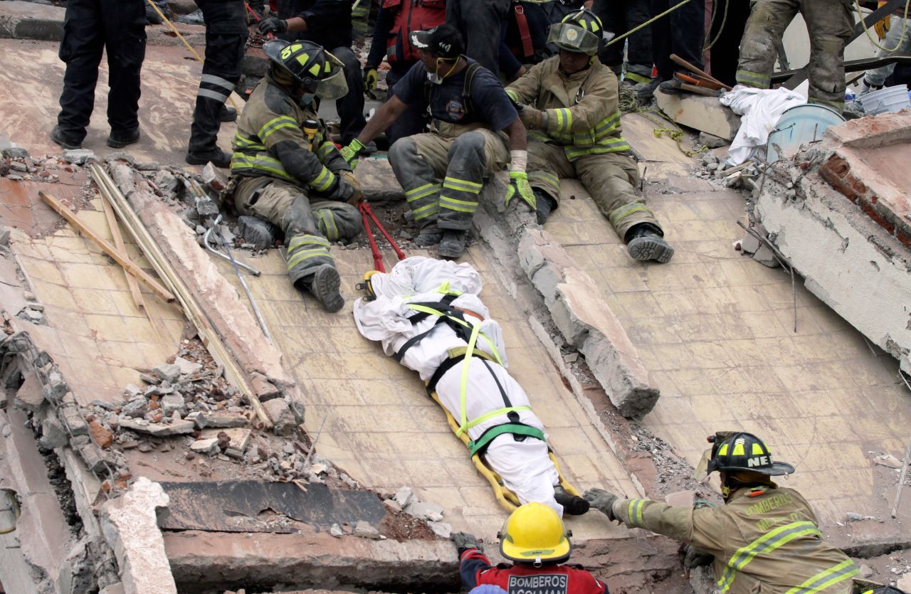 Rescuers and firefighters lower a corpse from a house in Mexico City on September 20.