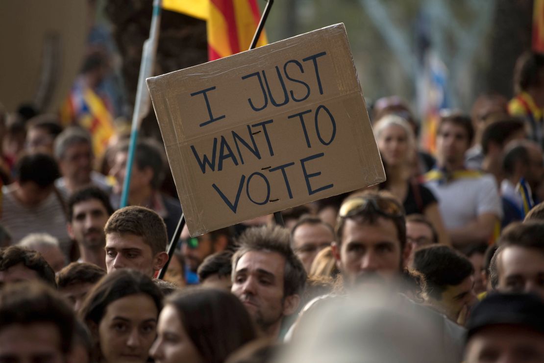 A banner reading "I just want to vote" is seen as demonstrators gather outside the Catalan high court. 