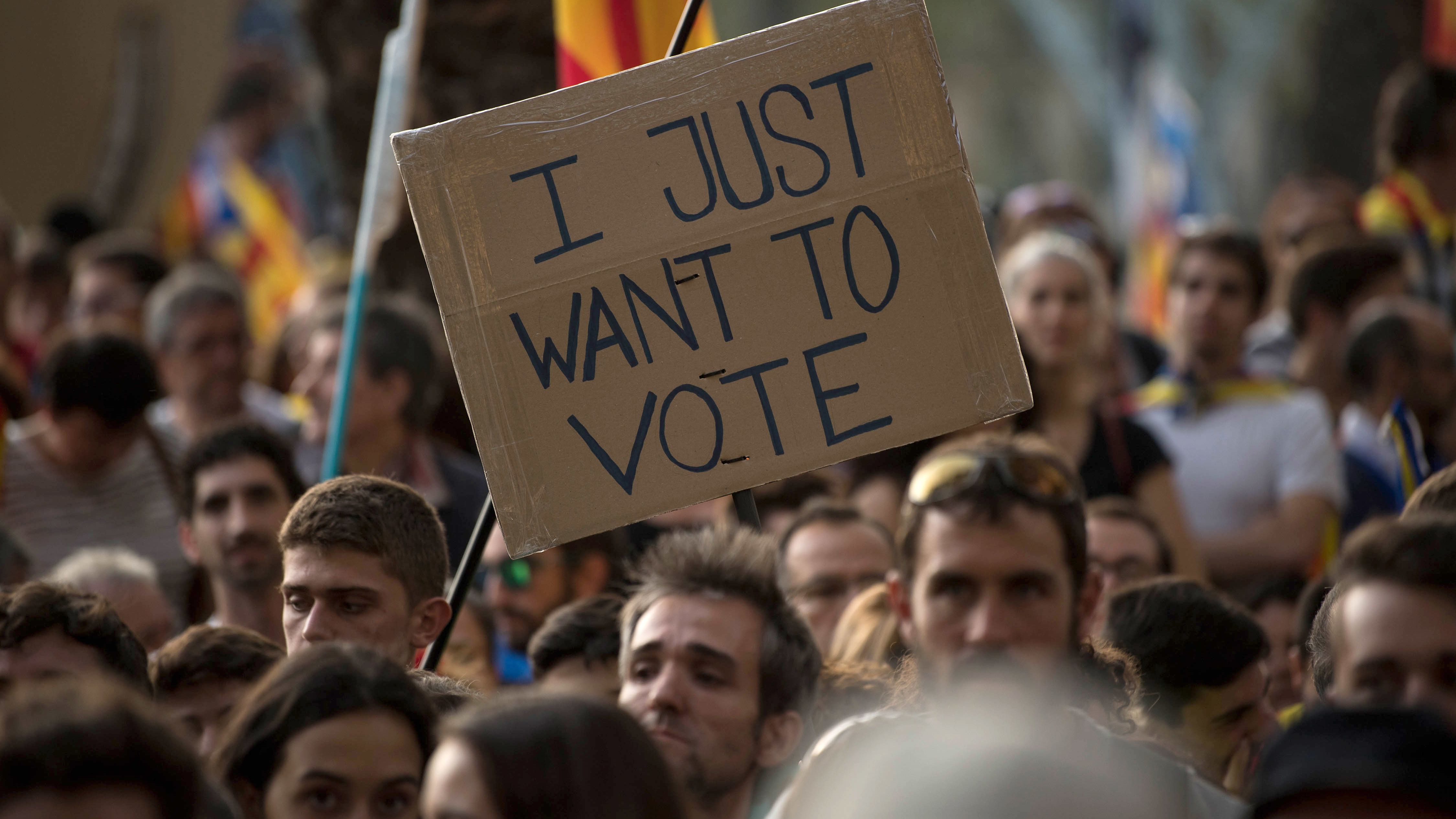 A banner reading "I just want to vote" is seen as demonstrators gather outside the Catalan high court. 