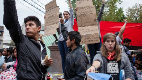 Young volunteers hand out face protection and call for silence while rescue workers listen for signs of life at the site on Thursday.