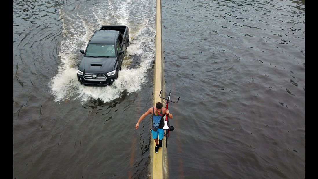 A man walks on a highway divider while carrying his bicycle through San Juan, Puerto Rico, on Thursday, September 21. 