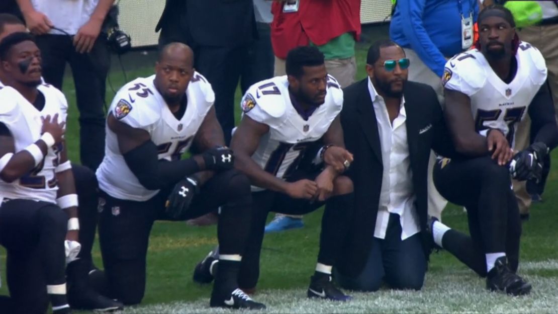 Terrell Suggs, No. 55, and Baltimore Ravens legend Ray Lewis, wearing a sport coat, kneel before Sunday's game. 
