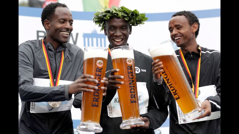 From left, Guye Adola, Eliud Kipchoge and Mosinet Geremew hold giant glasses of<br />beer Sunday, September 24, during the medal ceremony for the Berlin Marathon. Kipchoge, a Kenyan, won the race. Adola and Geremew, who are both Ethiopian, finished in second and third.