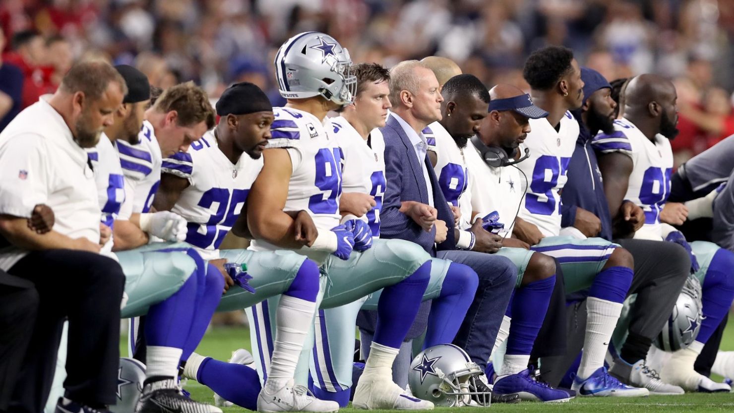 Members of the Dallas Cowboys link arms and kneel during the National Anthem before the start of the NFL game against the Arizona Cardinals on September 25