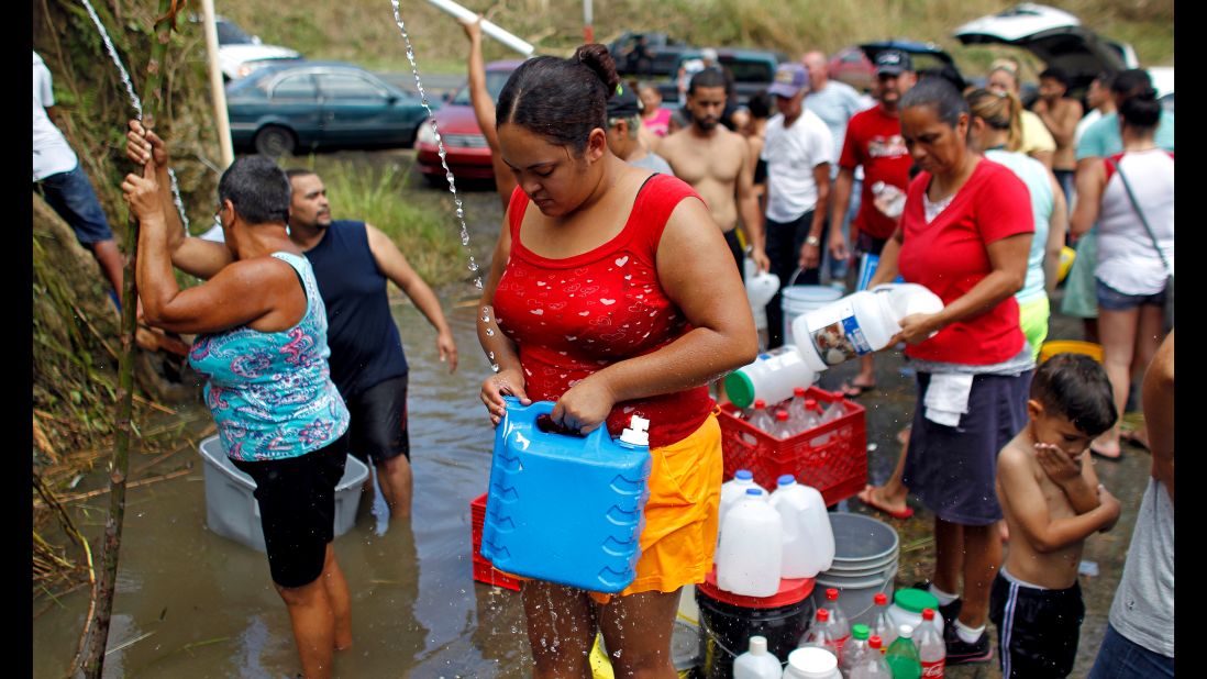 People collect water from a natural spring created by landslides in Corozal, Puerto Rico, on Sunday, September 24. Puerto Rican Gov. Ricardo Rosselló said the island faces a humanitarian crisis.