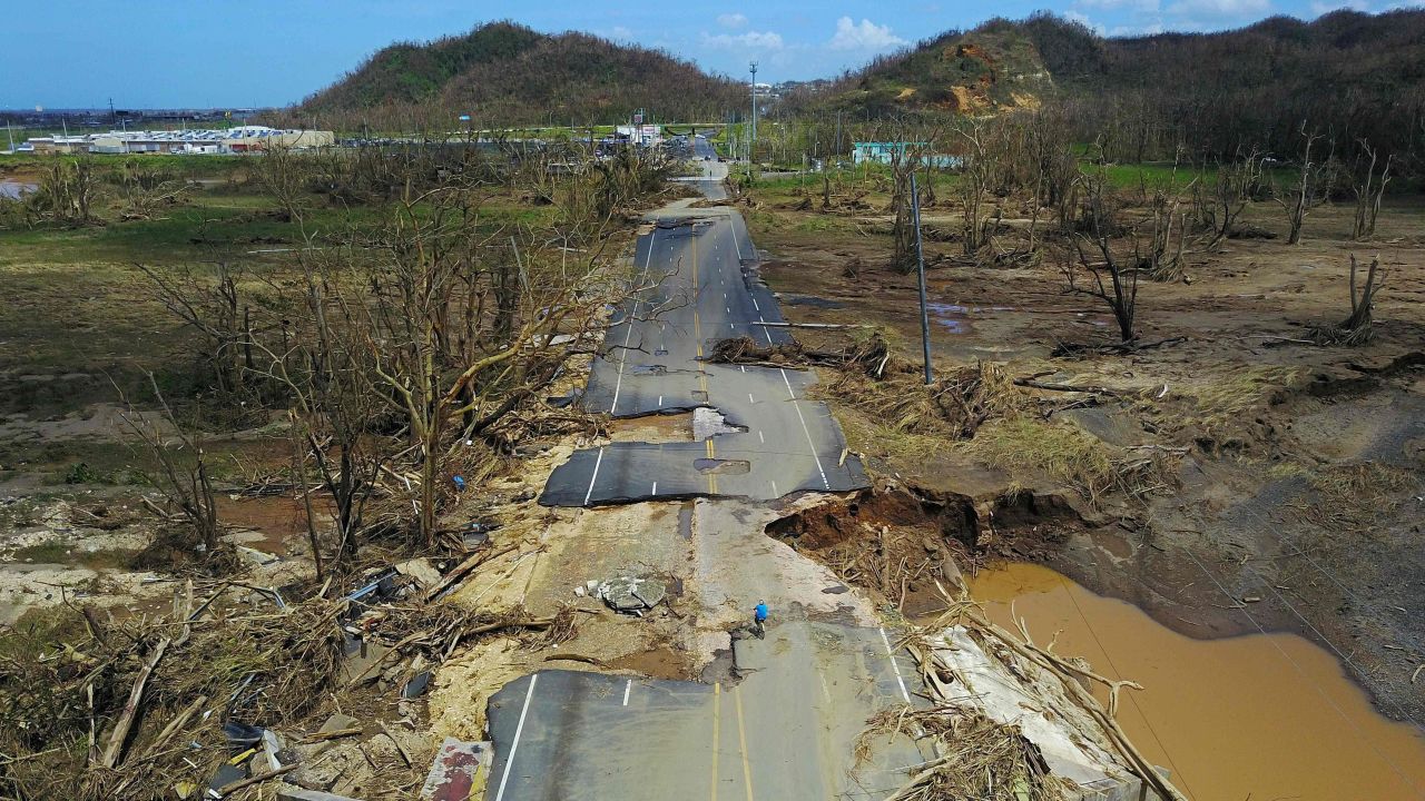 TOPSHOT - A man rides his bicycle through a damaged road in Toa Alta, west of San Juan, Puerto Rico, on September 24, 2017 following the passage of Hurricane Maria.
Authorities in Puerto Rico rushed on September 23, 2017 to evacuate people living downriver from a dam said to be in danger of collapsing because of flooding from Hurricane Maria. / AFP PHOTO / Ricardo ARDUENGORICARDO ARDUENGO/AFP/Getty Images