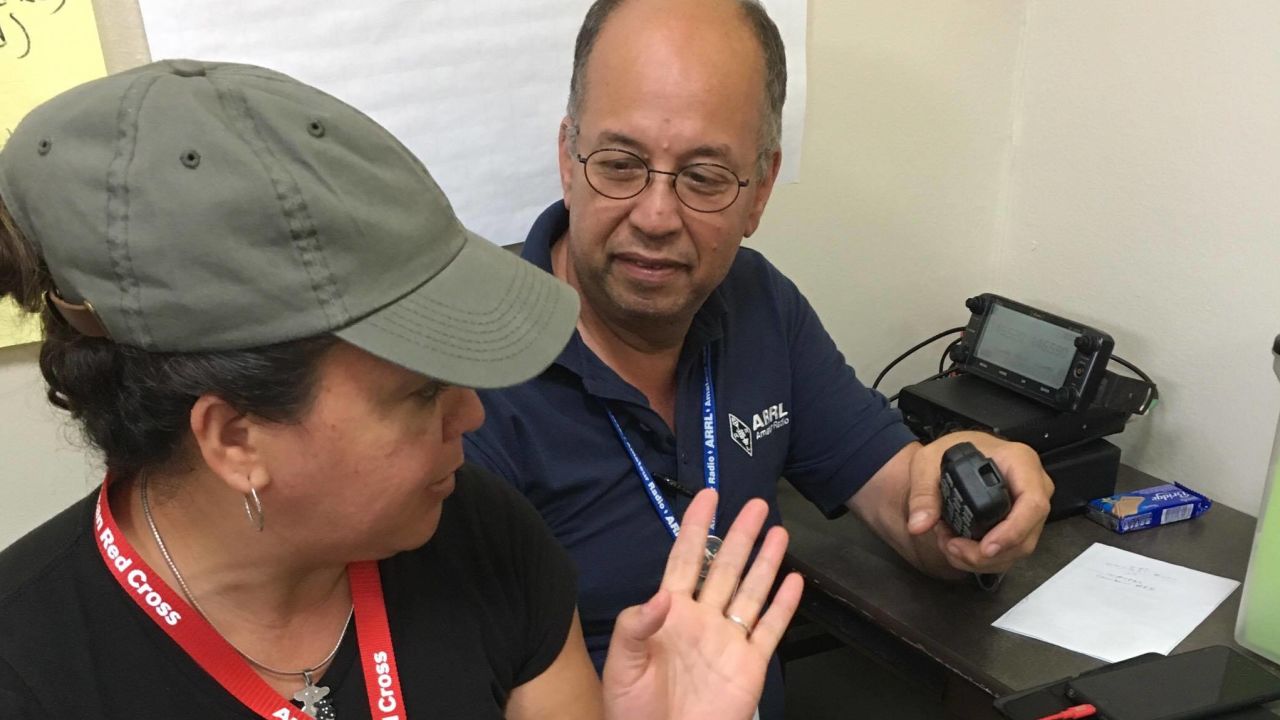 Oscar Resto works with another volunteer to pass along information at the Red Cross headquarters in San Juan, Puerto Rico.