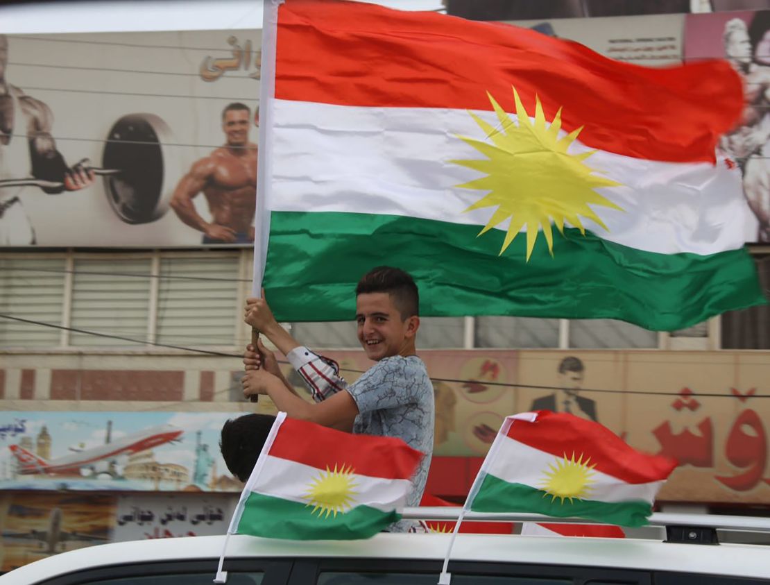 A young Kurdish boy waves the Kurdish flag from a car on the streets of Irbil.