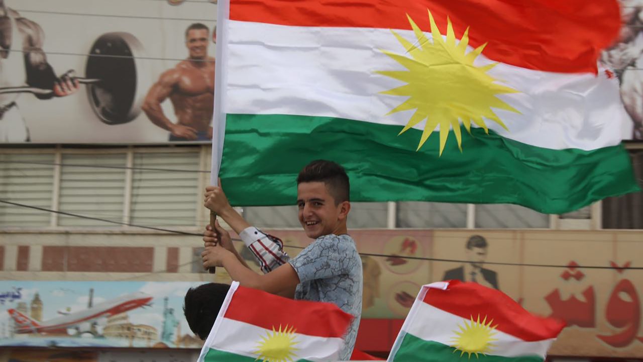 A young Kurdish boy waves the Kurdish flag from a car on the streets of Irbil.