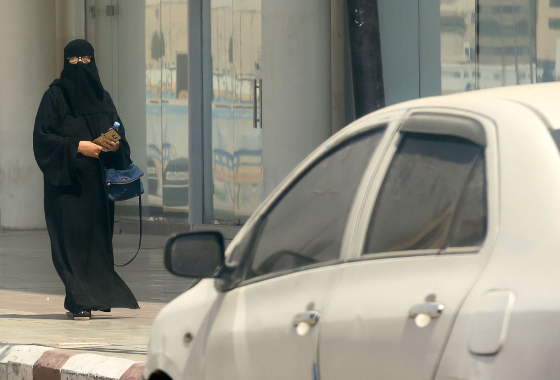 A Saudi woman walks near car down a street in the Saudi capital Riyadh on September 27, 2017.